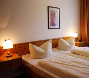 two beds in a hotel room with two lamps at Chiemgau Appartements in Inzell