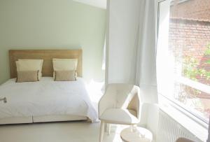 1 dormitorio con 1 cama, 1 silla y 1 ventana en chambre d'hôte M et Mme Collet en Lille
