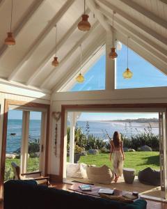 a woman standing in a living room with a large window at Little Church Bay in New Plymouth