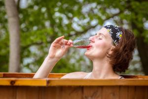 uma mulher a beber um copo de vinho numa banheira em Wildberghof em Markt Nordheim