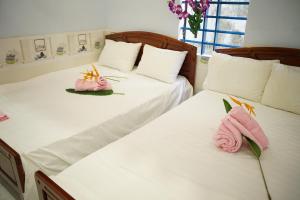 2 posti letto in una camera con asciugamani rosa di Bai Huong homestay a Hoi An