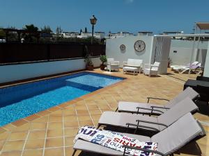 a swimming pool with chairs and a table at Las Arecas Mansion in Playa Blanca