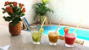 four drinks sitting on a table next to a pool at Pousada Ilha das Conchas in Guarujá