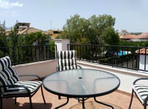 a glass table and two chairs on a balcony at Casa modernista in La Zubia
