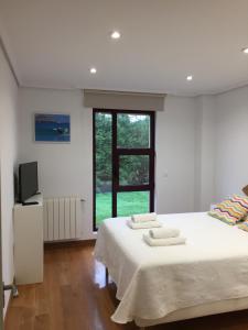 a bedroom with a bed with white sheets and a window at Somo Surfskate hostel in Castanedo