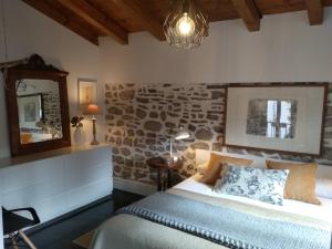 a bedroom with a bed and a stone wall at Batxillerenea in Doneztebe