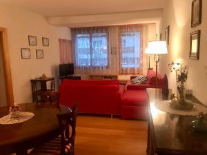 a living room with a red couch and a table at Crans center and close to the ski lifts in Crans-Montana