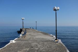 a pier with benches and lights on the water at Hotel Pelagos Studios in Platána