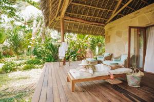 a person laying on a bed on a porch at Tulia Zanzibar Unique Beach Resort in Pongwe