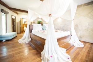 a bedroom with a bed with white drapes at Tulia Zanzibar Unique Beach Resort in Pongwe