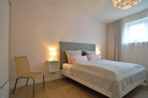 um quarto com uma cama, uma cadeira e um lustre em Grey House Apartments Grossbeeren em Großbeeren
