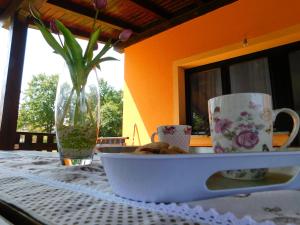 a table with a bowl and cups and a vase on it at Apartment Petrovic in Slunj