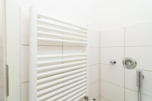 La salle de bains est pourvue d'une douche avec du carrelage blanc. dans l'établissement Private apartments with direct subway entrance, à Fürth