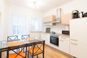 a kitchen with white cabinets and a table and chairs at Private apartments with direct subway entrance in Fürth
