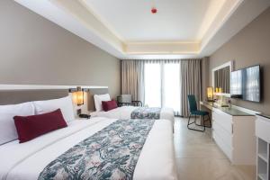 a hotel room with two beds and a desk at Woovo Phuket Patong - SHA Extra Plus in Patong Beach