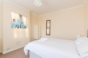a bedroom with a white bed and a painting on the wall at Well presented 2 bedroom house - sleeps four in Leamington Spa