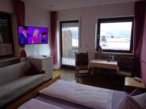 a living room with a couch and a tv on the wall at Pension Schamberger in Neukirchen beim Heiligen Blut