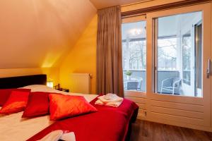 een slaapkamer met een bed met rode kussens en een raam bij De Valkhoeve in Mill