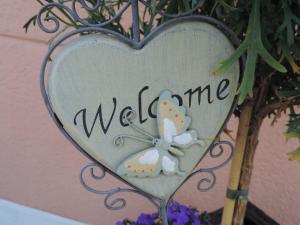 a heart shaped sign that says welcome with a butterfly at Hotel Spöl Restaurant in Zernez