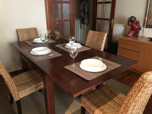 a wooden table with chairs and plates and wine glasses at Apartamento La Sirena Brazomar in Castro-Urdiales