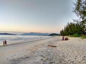 a group of people walking on the beach at The Hidden Gems in Pantai Cenang