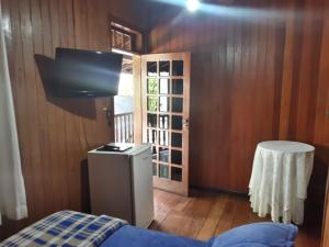 a room with a bed and a television and a door at Hotel Montanus in Nova Friburgo