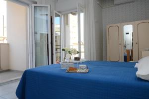 ein blaues Bett mit einer Tasse Kaffee und einem Handtuch in der Unterkunft Pensione Elena in Misano Adriatico