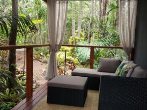 a porch with a couch and chairs on a deck at Forest Lodge: Little Villa in Agnes Water