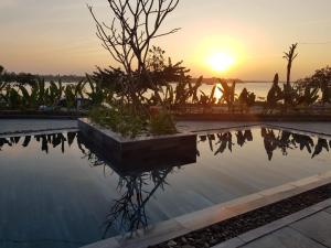 a pool of water with a sunset in the background at The Corner Riverside Villa in Hoi An
