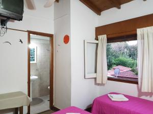 una camera con letto e finestra e un bagno di Hotel El Cisne a Villa Gesell