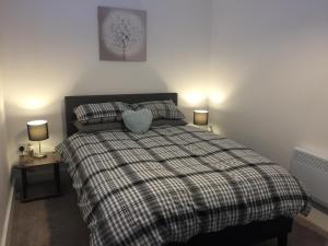 a bedroom with a bed with a plaid blanket and two lamps at St Leonards cottage in Newark upon Trent
