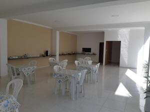 a dining room with white tables and white chairs at Pousada Canto dos Corais in Maragogi