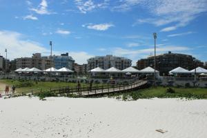 einen Strand mit einem Haufen weißer Regenschirme und Gebäude in der Unterkunft Apto confortável de 3 quartos-Cabo Frio in Cabo Frio