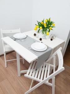 トルンにあるApartament Skandiaの白いテーブルと椅子2脚、花瓶