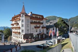 a large building with cars parked in a parking lot at Hotel Colbricon in San Martino di Castrozza