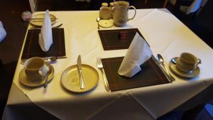 a table with plates and cups and utensils on it at Ivanhoe Guest House in Inverness