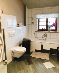 uma casa de banho com um WC, uma banheira e uma janela. em Ferienwohnung Auszeit in Ausnang em Leutkirch im Allgäu