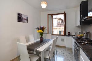 een keuken met een tafel met witte stoelen en een raam bij Appartamento Fabris in Venetië