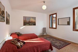 een slaapkamer met twee rode bedden en een schilderij aan de muur bij Appartamento Fabris in Venetië