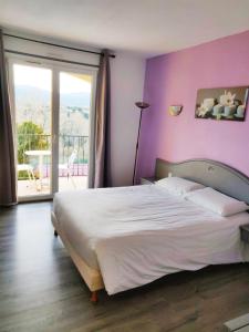 a bedroom with a large bed with a purple wall at Le Neoulous in Le Boulou