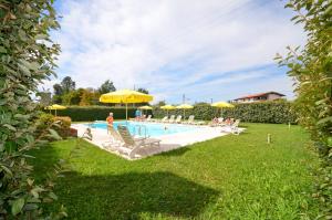 a swimming pool with lawn chairs and umbrellas at Casa Miniscalchi in Marinella