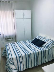 1 dormitorio con 1 cama con manta a rayas en Apartamento Copacabana, en Río de Janeiro