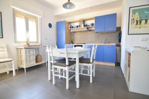 a kitchen with blue cabinets and a white table and chairs at Sitting on the beach in Punta Secca
