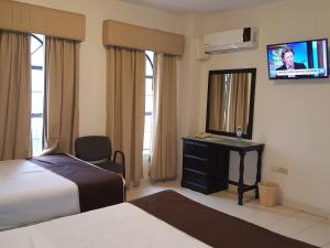 a hotel room with two beds and a television at Hotel Roma in Matamoros