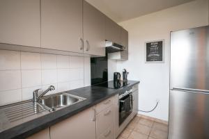 a kitchen with a sink and a stainless steel refrigerator at Sweet Home Disneyland Paris - Cosy Apartment WiFi in Bussy-Saint-Georges