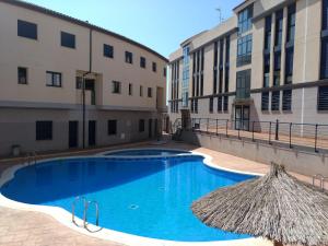 a swimming pool with a straw umbrella and some buildings at Residencial La Llosa in La Llosa