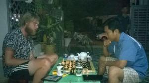 Dois homens sentados numa mesa a jogar xadrez. em Minh Duc Hotel - Phan Rang em Phan Rang-Tháp Chàm