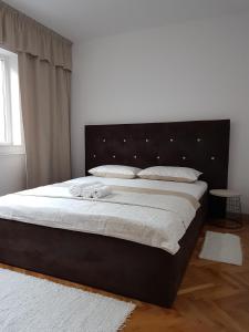 een slaapkamer met een groot bed met een zwart hoofdeinde bij Tania Apartament in Oradea