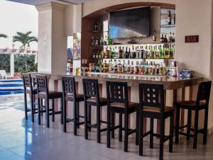 a bar with bar stools and a television above it at Hotel RRU Diamante in Acapulco