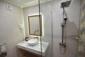 a bathroom with a sink and a shower with a mirror at Sahara Hotel in Svilengrad